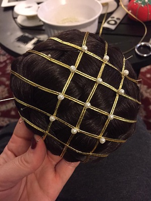 Faux braided chignon with gold and pearl hairnet being attached